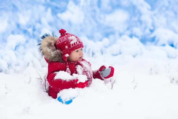 Barnet leker med snö på vintern. — Stockfoto