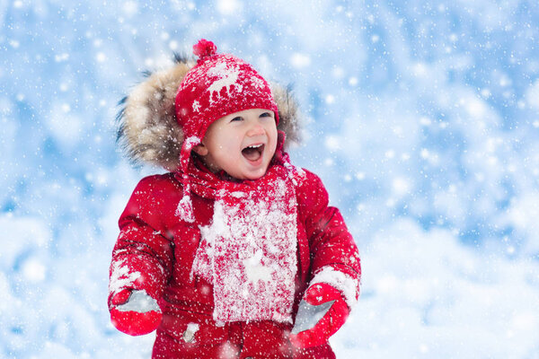 Baby playing with snow in winter. 