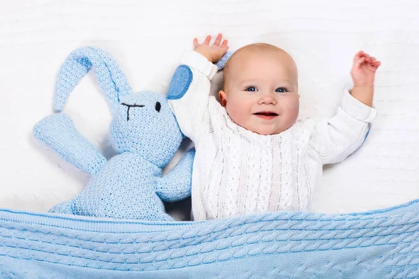 Bebé niño jugando con azul de punto conejito juguete — Foto de Stock