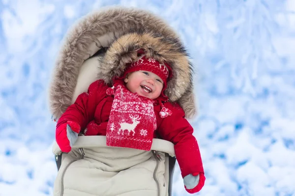 Baby in stroller in winter park with snow — Stock Photo, Image