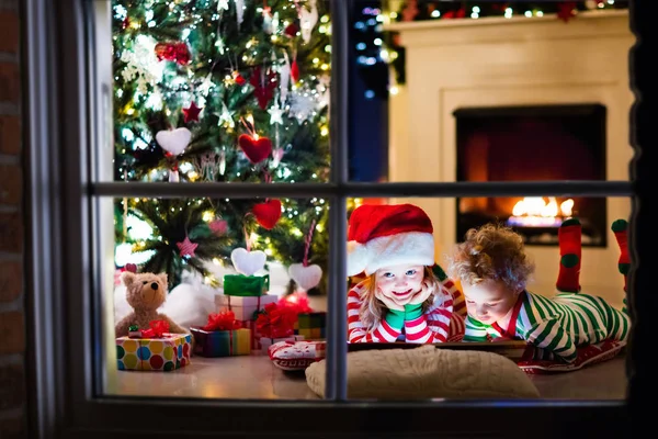 Crianças de pijama debaixo da árvore de Natal — Fotografia de Stock