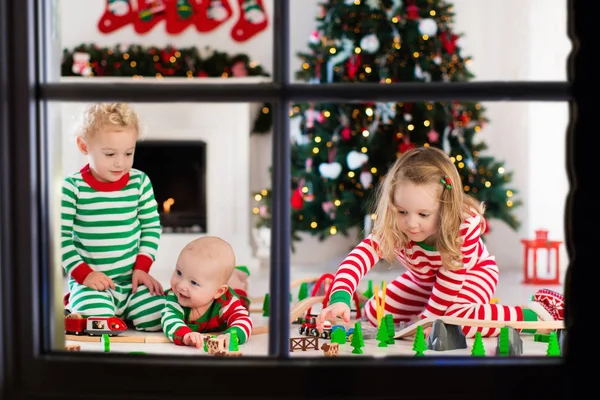 Дети играют с игрушечной железной дорогой в рождественское утро — стоковое фото