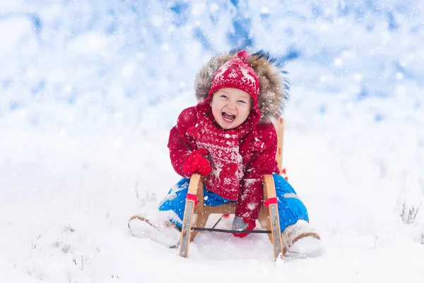 Los niños juegan en la nieve. Paseo en trineo de invierno para niños —  Fotos de Stock