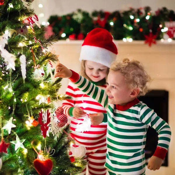 Barn i pyjamas under julgranen — Stockfoto