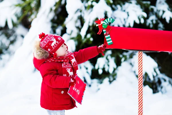 Dziecko z list do Santa w Boże Narodzenie mail box w śniegu — Zdjęcie stockowe