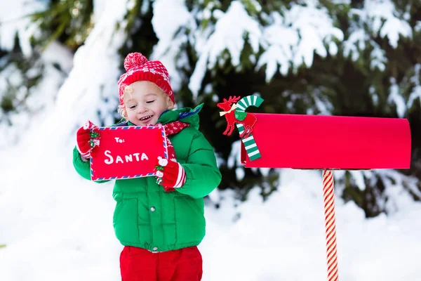 Dítě s dopis do Santa na Vánoce mail box ve sněhu — Stock fotografie