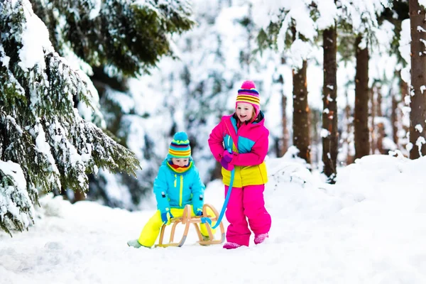 Anak-anak bermain salju di atas kereta salju di taman musim dingin — Stok Foto
