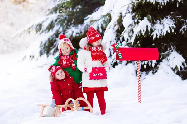 Děti s dopis do Santa na Vánoce mail box ve sněhu — Stock fotografie