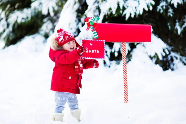 Dítě s dopis do Santa na Vánoce mail box ve sněhu — Stock fotografie