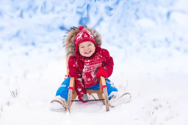 Los niños juegan en la nieve. Paseo en trineo de invierno para niños —  Fotos de Stock