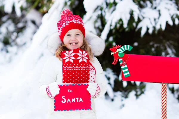 Child with letter to Santa at Christmas mail box in snow — Stock Photo, Image