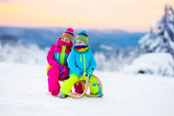 Children play in snow on sleigh in winter park — Stock Photo, Image