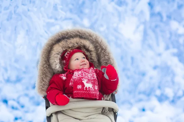 Bambino in passeggino nel parco invernale con neve — Foto Stock