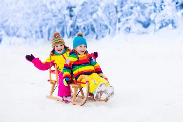 As crianças brincam na neve. Passeio de trenó de inverno para crianças — Fotografia de Stock