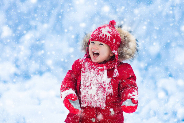 Baby playing with snow in winter. 