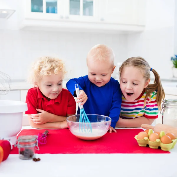 Kinderen bakken een taart in witte keuken — Stockfoto