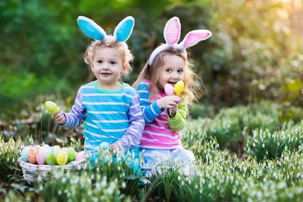 Enfants avec des oreilles de lapin sur la chasse aux œufs de Pâques — Photo