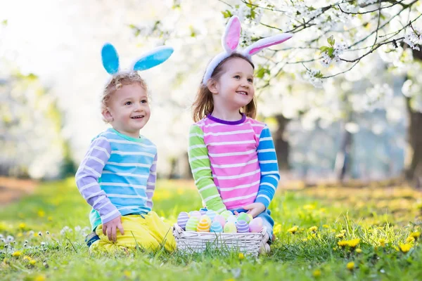 Easter egg hunt. Kids with bunny ears in spring garden. — Stock Photo, Image