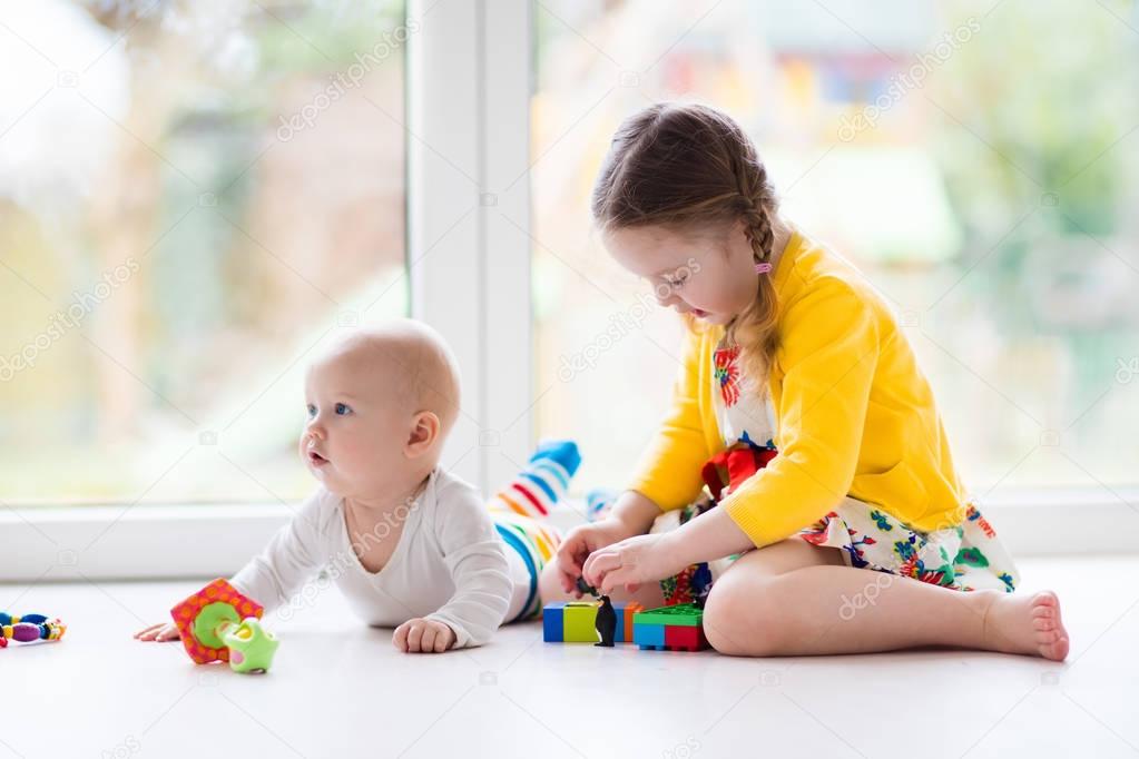 Sister and baby brother play with toy blocks