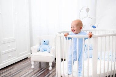 Beyaz kreş yatakta duran erkek bebek