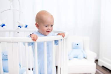 Beyaz kreş yatakta duran erkek bebek