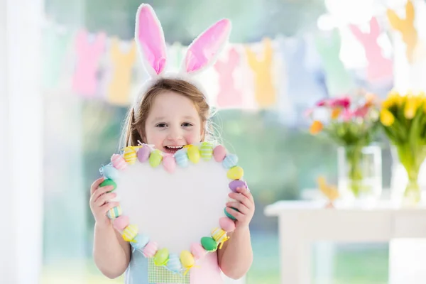 Маленькая девочка в кроличьих ушах на пасхальных яйцах — стоковое фото