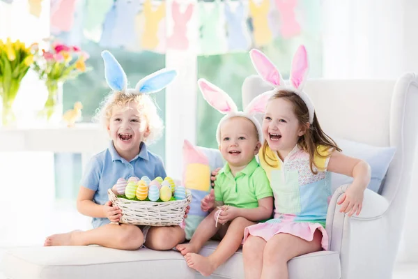 Enfants avec des oreilles de lapin sur la chasse aux œufs de Pâques — Photo