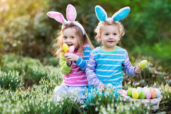 Niños con orejas de conejo en la búsqueda de huevos de Pascua — Foto de Stock