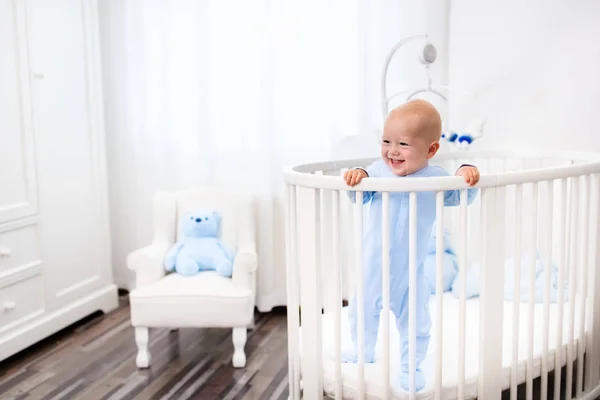 Babyjongen permanent in bed in witte kinderkamer — Stockfoto