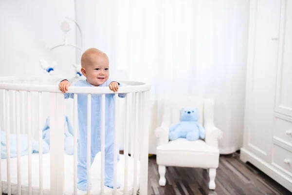 Babyjongen permanent in bed in witte kinderkamer — Stockfoto