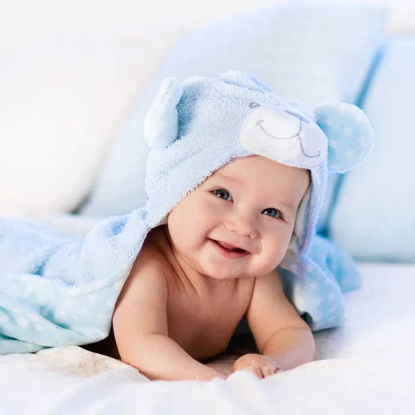 Baby i håndkle etter bad i sengen – stockfoto