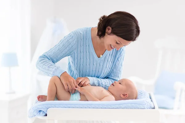 Mother changing diaper to baby boy