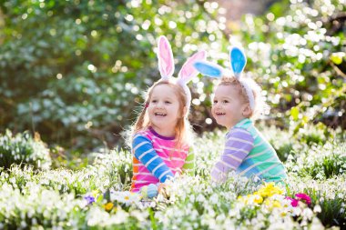 Çocuklar çiçeklenme içinde Paskalya yumurtası avına Bahçe bahar