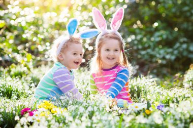 Çocuklar çiçeklenme içinde Paskalya yumurtası avına Bahçe bahar