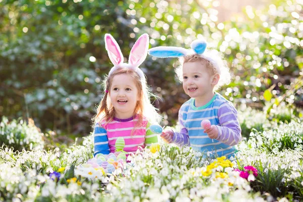 Niños en la búsqueda de huevos de Pascua en el floreciente jardín de primavera — Foto de Stock