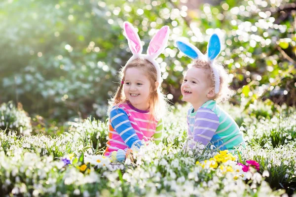 Niños en la búsqueda de huevos de Pascua en el floreciente jardín de primavera — Foto de Stock