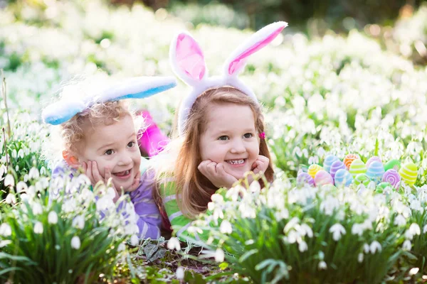 Kids on Easter egg hunt in blooming spring garden — Stock Photo, Image