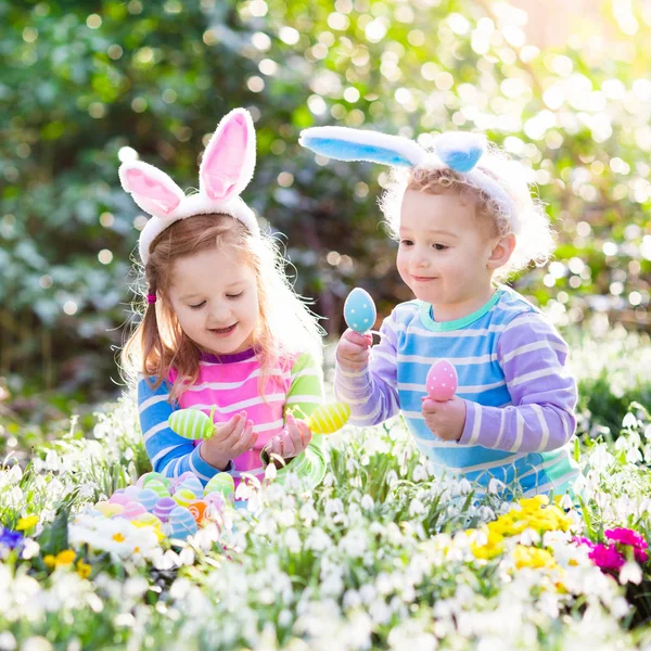 Niños en la búsqueda de huevos de Pascua en el floreciente jardín de primavera —  Fotos de Stock