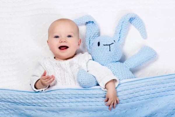 Bébé garçon jouer avec lapin jouet dans le lit — Photo