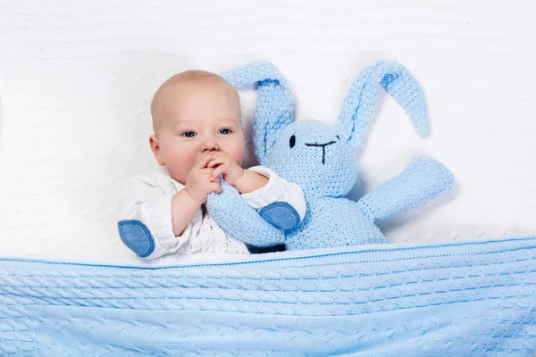 Baby boy playing with bunny toy in bed — Stock Photo, Image