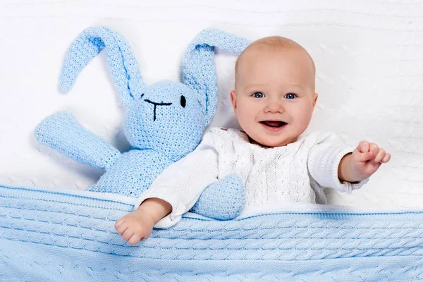 Baby boy playing with bunny toy in bed — Stock Photo, Image