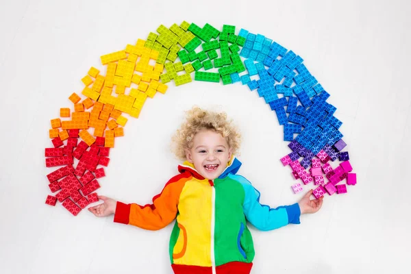 Kind spielt mit Regenbogen-Plastikklötzen — Stockfoto