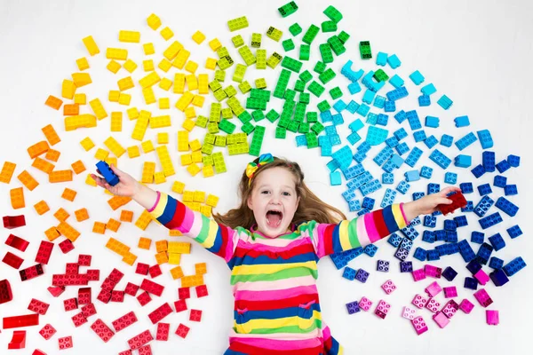 Kind spielt mit Regenbogen-Plastikklötzen — Stockfoto
