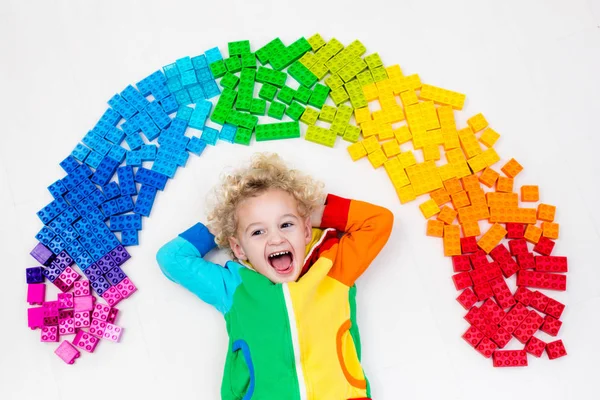 Kind spielt mit Regenbogen-Plastikklötzen — Stockfoto