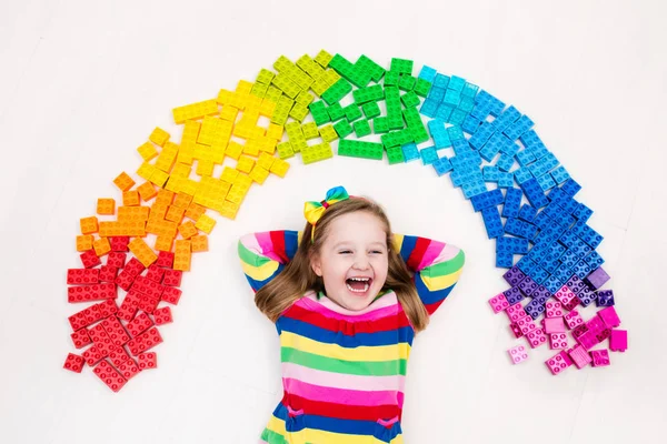 Kind spielt mit Regenbogen-Plastikklötzen — Stockfoto