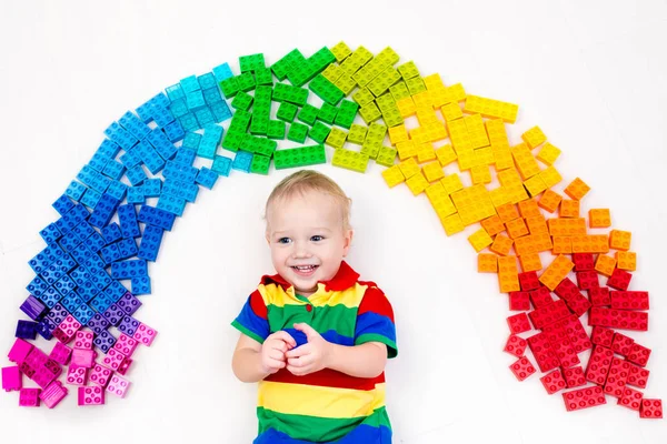 Kind spielt mit Regenbogen-Plastikklötzen — Stockfoto