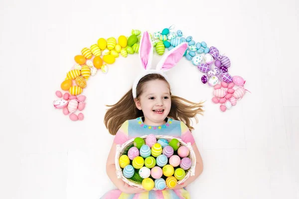 Niño en la búsqueda de huevos de Pascua. Huevos arcoiris pasteles . — Foto de Stock