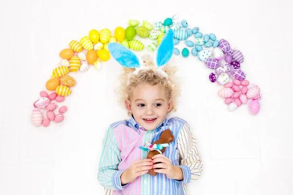 Niño en la búsqueda de huevos de Pascua. Huevos arcoiris pasteles . — Foto de Stock