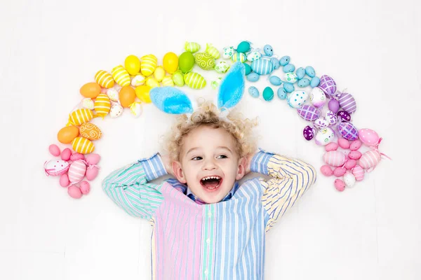 Niño en la búsqueda de huevos de Pascua. Huevos arcoiris pasteles . —  Fotos de Stock