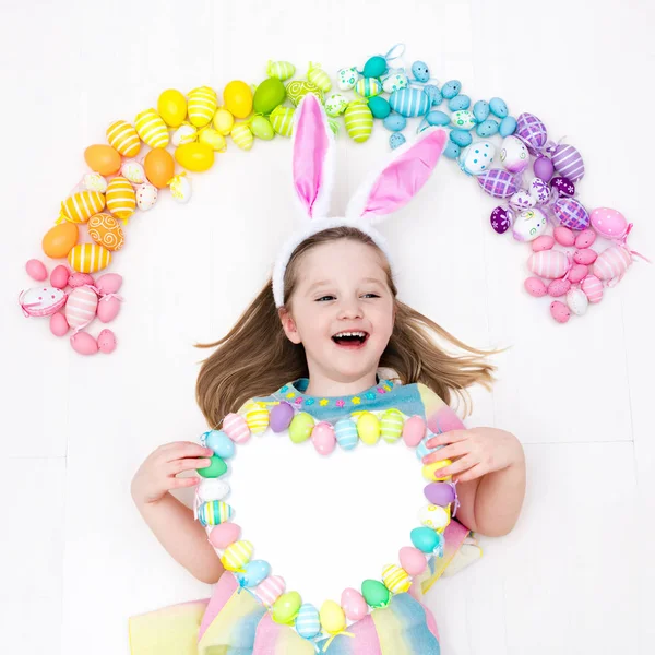 Niño en la búsqueda de huevos de Pascua. Huevos arcoiris pasteles . — Foto de Stock